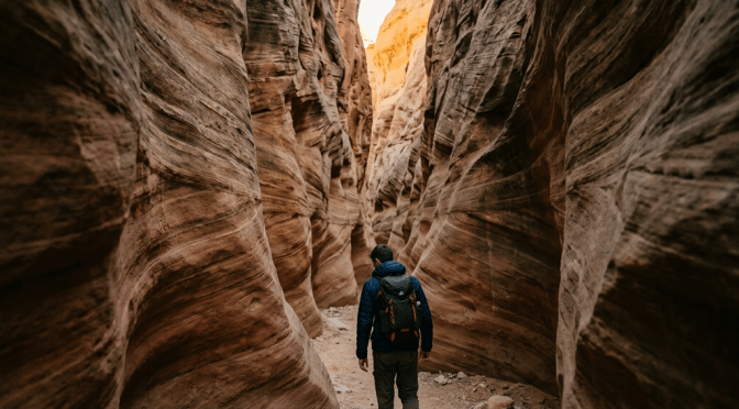 Hiker walking through narrow slot canyon with textured rock walls