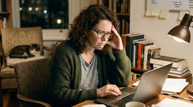 Person studying at a laptop beside notes, books, and a planning whiteboard